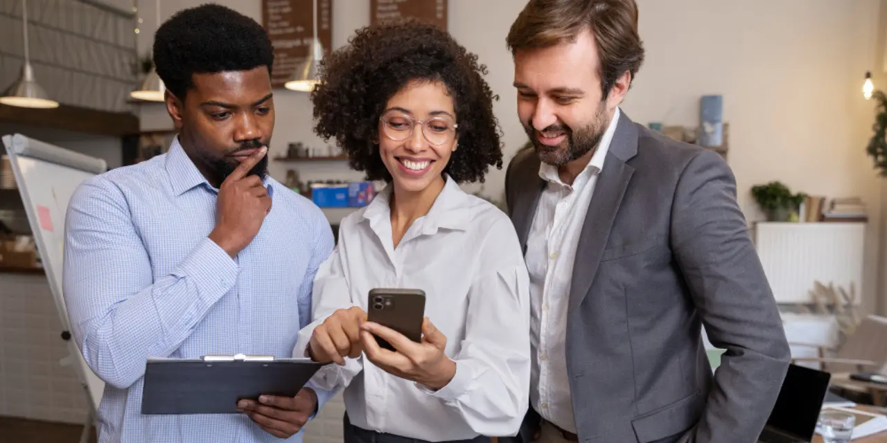 Grupo de profissionais analisando informações em um celular no ambiente de trabalho.