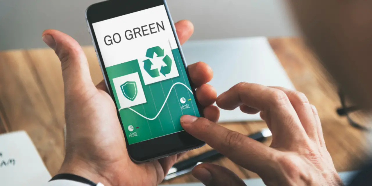 Persona que usa un teléfono inteligente que muestra la palabra “Go Green” y un ícono de reciclaje.