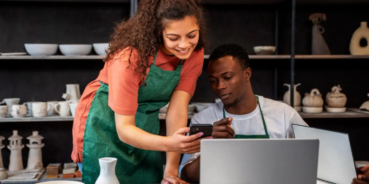 Empreendedores em workshop analisando informações no celular e laptop.