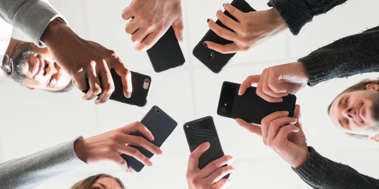 Grupo de pessoas segurando celulares em círculo.